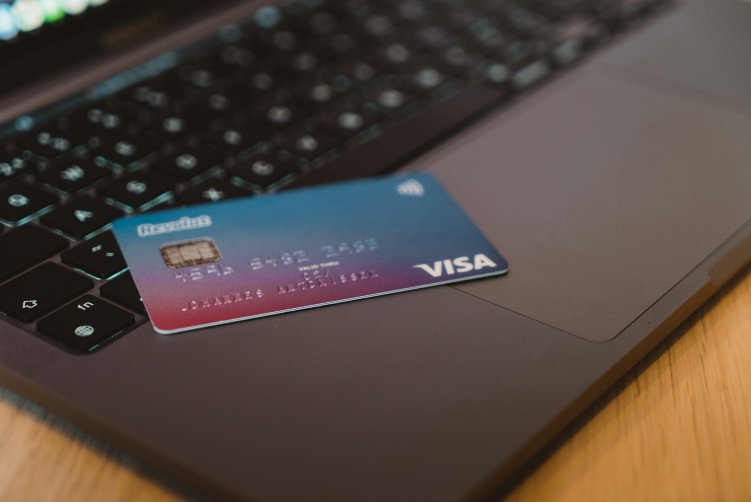 A purple and blue credit card on a great laptop keyboard